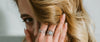 Loretana model intimate hand-to-hair pose with sterling silver filigree rings and bracelet, complete interchangeable jewelry guide. Kaunas.