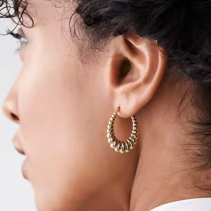 Close up of the 14K Gold Thick Twisted Hoops highlighting the rhythmic torsion and the high-polish 14K gold finish.
