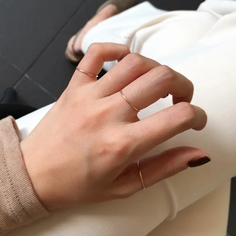 Hand wearing multiple 14K gold-plated stacking bands on adjacent fingers, hypoallergenic 925 sterling silver hallmarked in Kaunas.