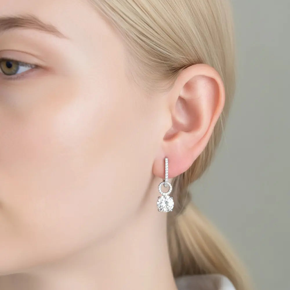 Close-up of a silver blue drop hoop earring showing the detachable mechanism and finish.