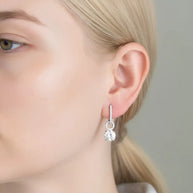 Close-up of a silver blue drop hoop earring showing the detachable mechanism and finish.