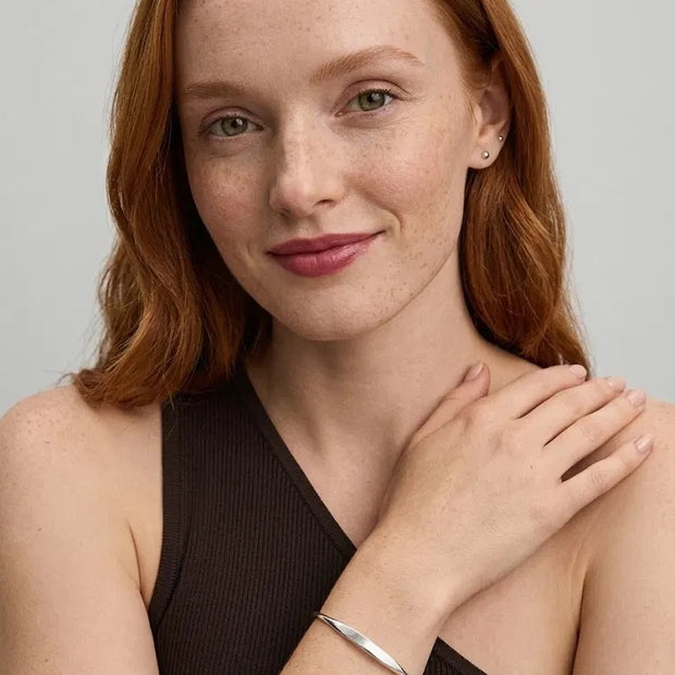 Smiling woman with her hand on her shoulder wearing the Personalized Letter Bangle in 925 sterling silver