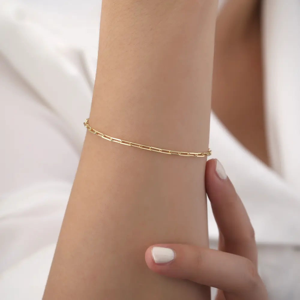 14K gold paperclip chain bracelet styled as the foundation of a curated golden stack