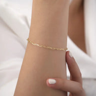 14K gold paperclip chain bracelet styled as the foundation of a curated golden stack