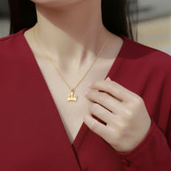 18K gold crown pendant styled in a curated layered neckline