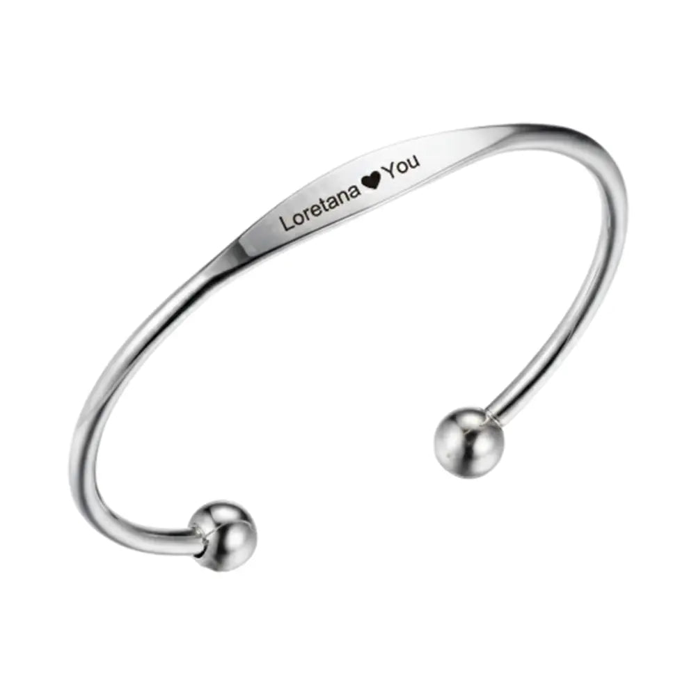 Close up of personalized silver cuff bracelet showing custom letter engraving
