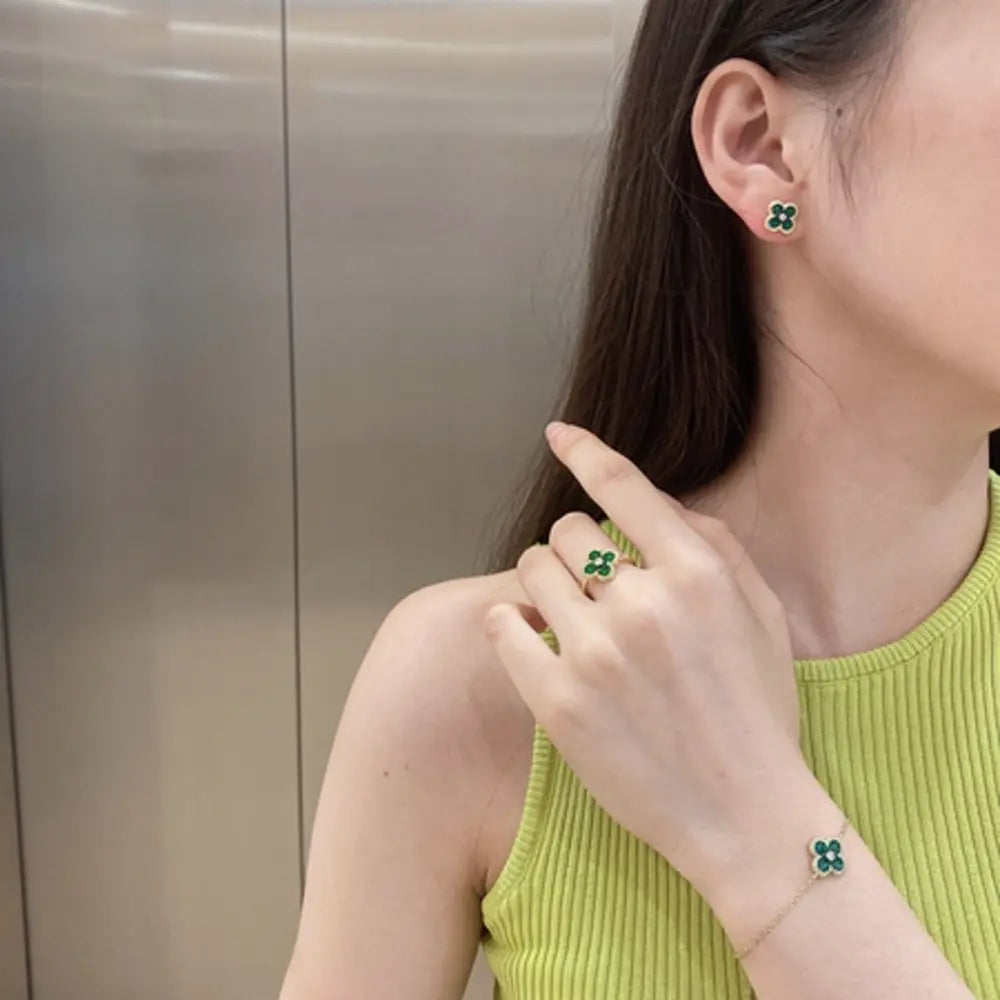 Lifestyle side view of a finger wearing the gold plated green clover ring with adjustable 925 silver band. Hallmarked Loretana piece, hand-finished in Kaunas.