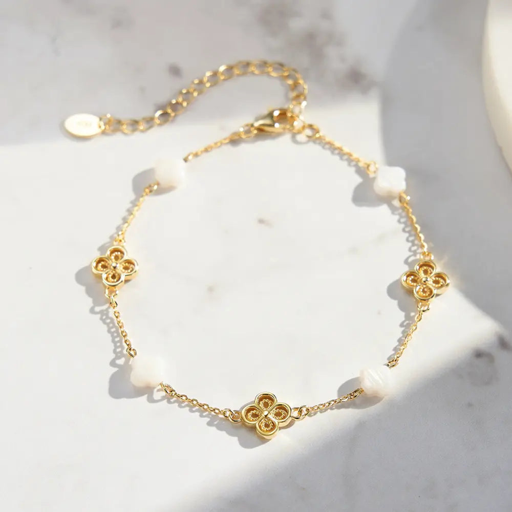 Woman wearing 14K gold clover pearl bracelet as a warm minimalist statement piece