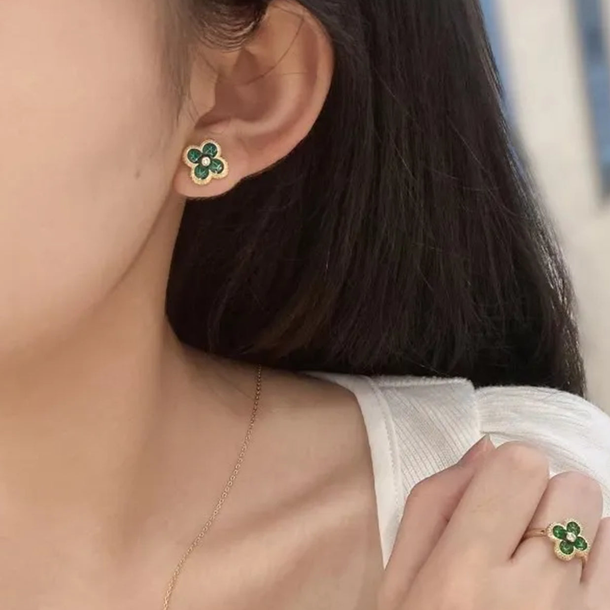 Close-up of a person wearing green clover earrings and a matching ring.