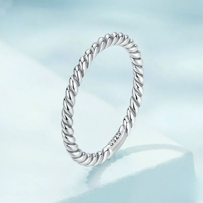 Close-up of woman's hand wearing the rhodium-plated 925 sterling silver twisted rope band stacked with other rings, minimalist styling. Hallmarked Loretana piece, hand-finished in Kaunas.
