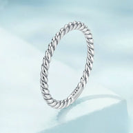 Close-up of woman's hand wearing the rhodium-plated 925 sterling silver twisted rope band stacked with other rings, minimalist styling. Hallmarked Loretana piece, hand-finished in Kaunas.