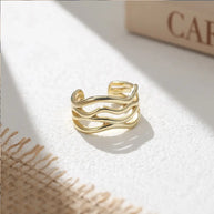 Top view of the twisted wave adjustable ring on white, 925 sterling silver with 14K gold plating and polished sculptural finish. Hallmarked Loretana piece, hand-finished in Kaunas.